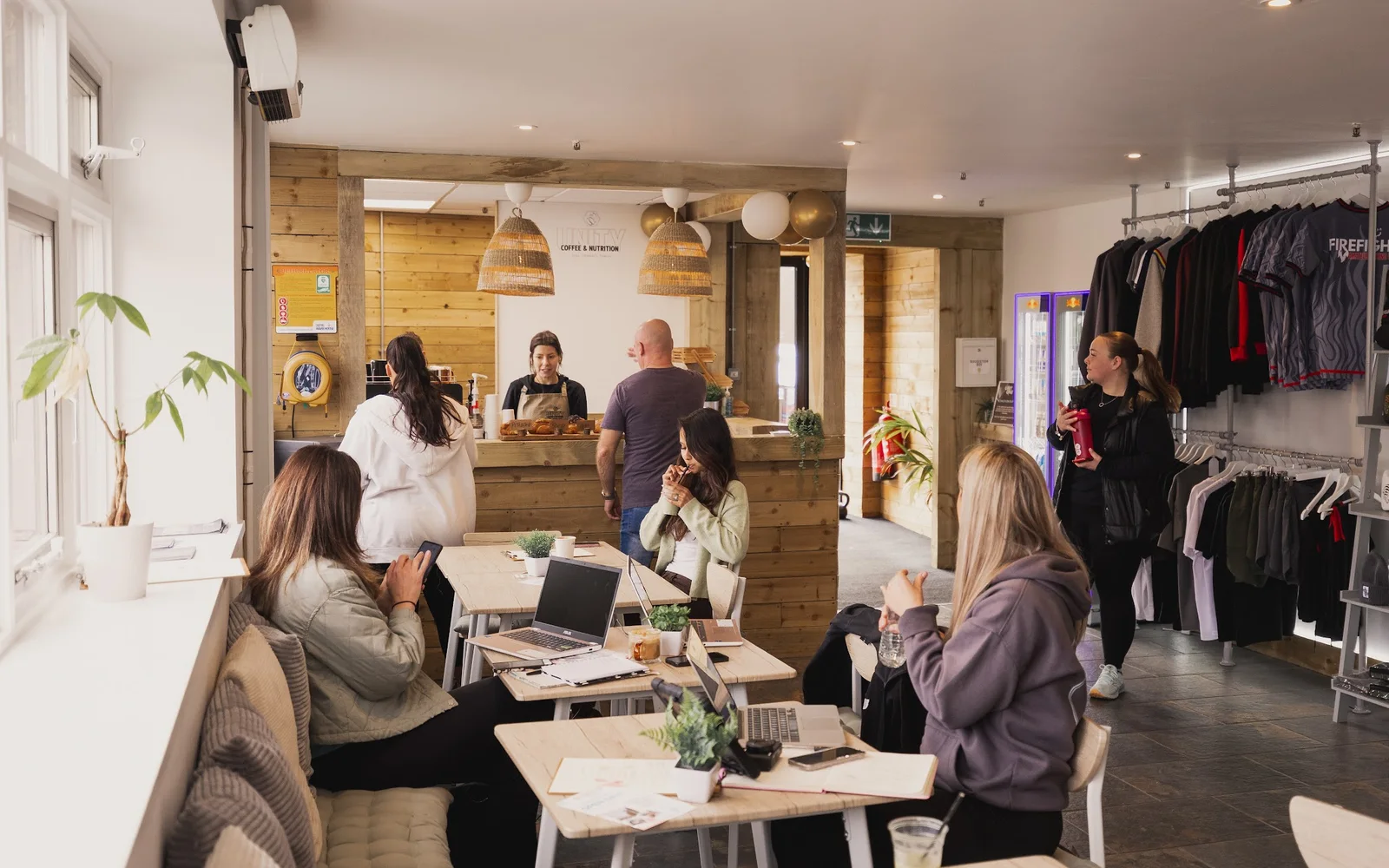 Customers chatting and using laptops in Unity's bright timber-lined café