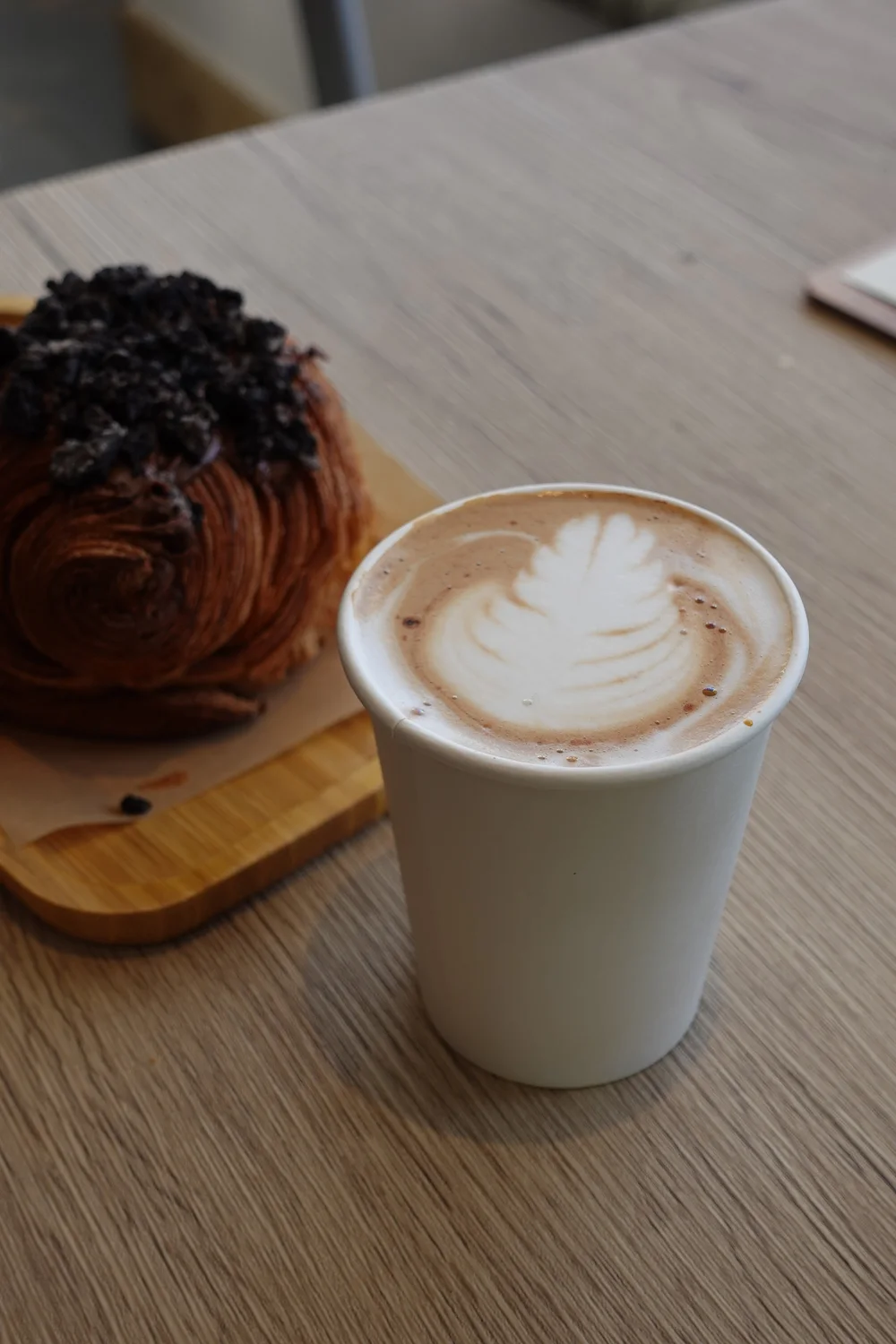 A Unity coffee with latte art beside a chocolate-topped pastry