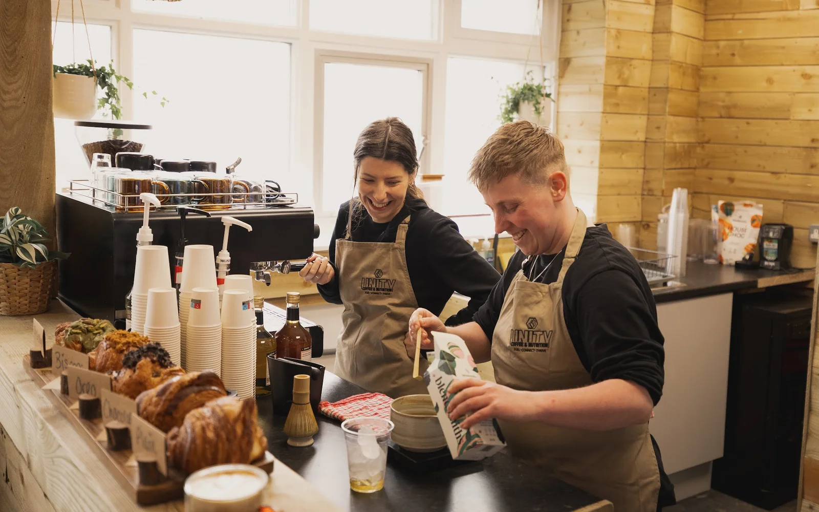 Two smiling Unity team members preparing drinks at the café counter