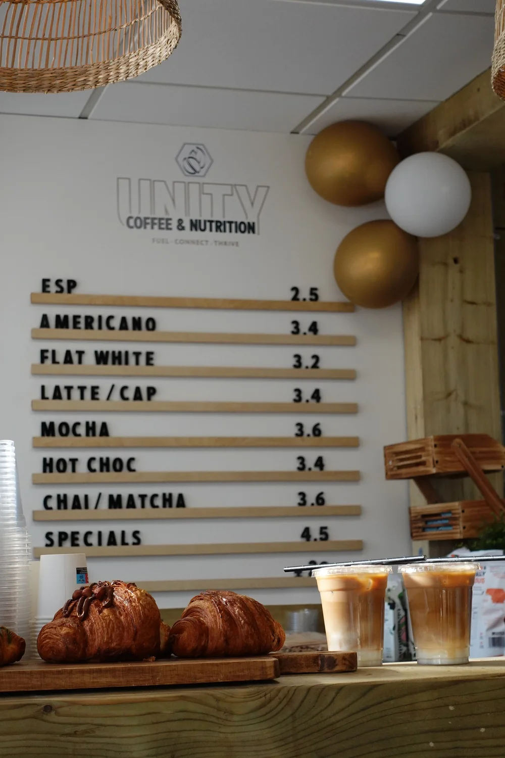 Iced coffees and pastries on Unity's counter below the drinks board