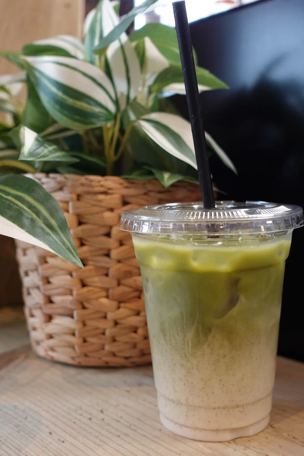 Iced matcha served at Unity beside a leafy plant